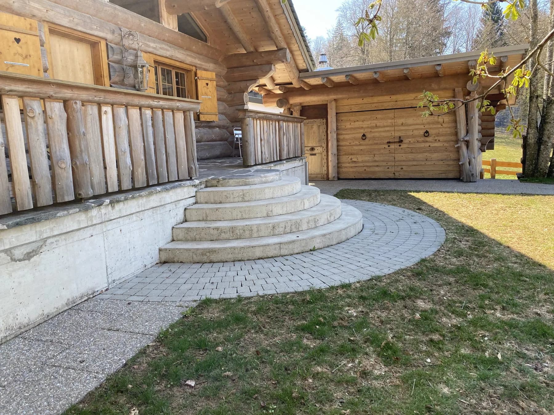 Blockhaus mit Echtholz-Garagentor in Scheunentor-Optik unter einem Holzvordach