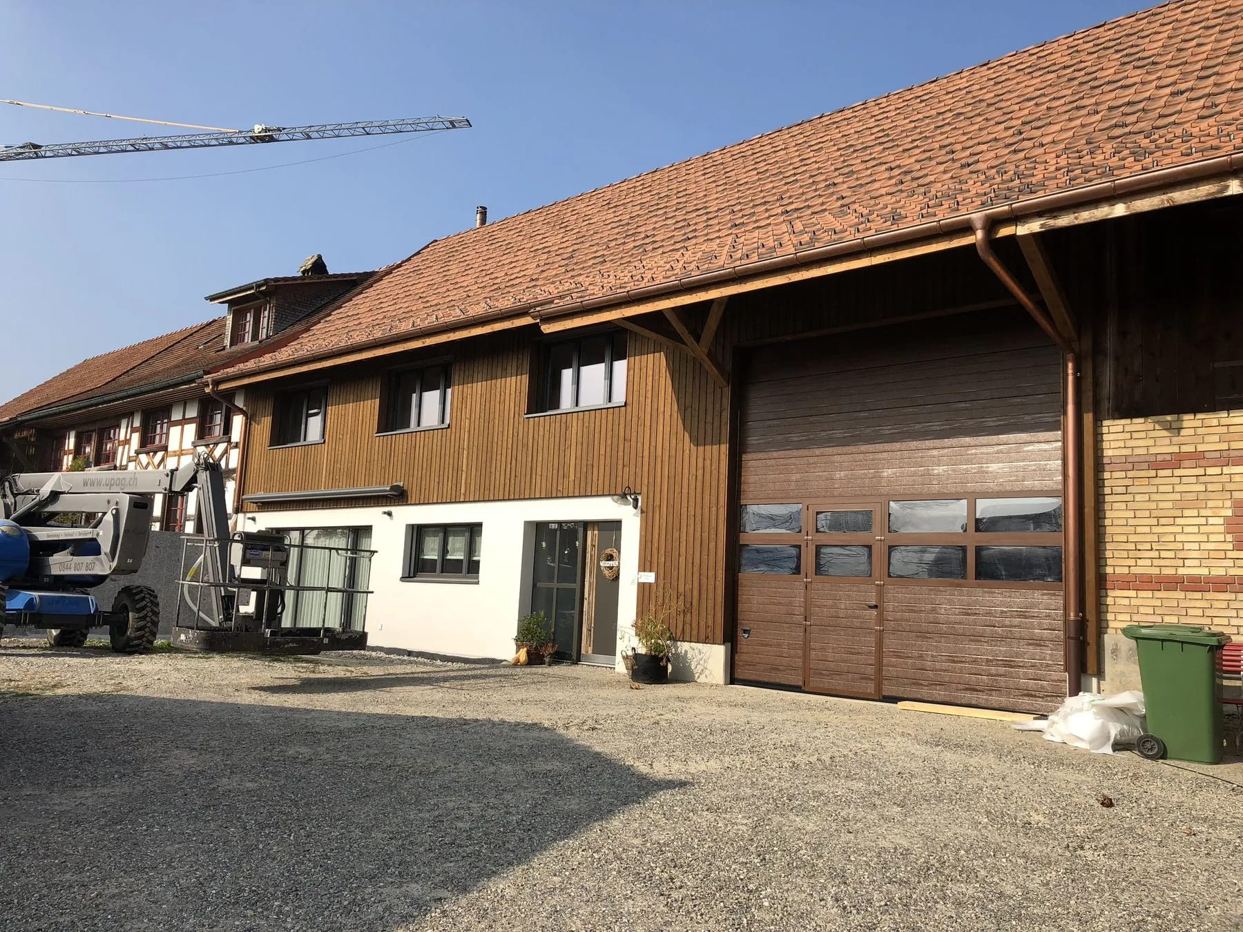 Umgebautes Bauernhaus mit Holzfassade und hohem Sektionaltor in Holzoptik mit Fensterband