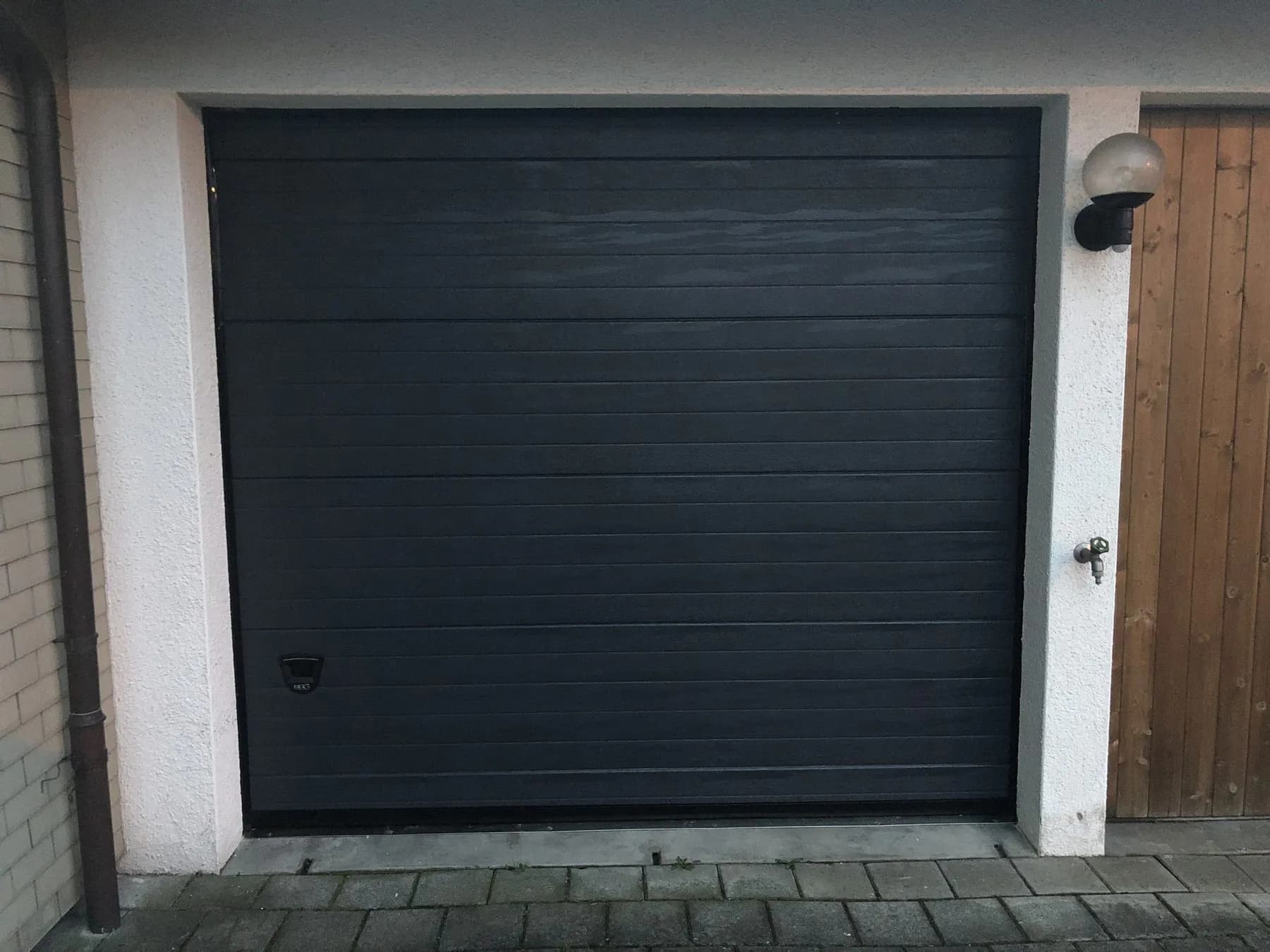 Anthrazitfarbenes Sektionaltor in einer Garage mit Holzverkleidung