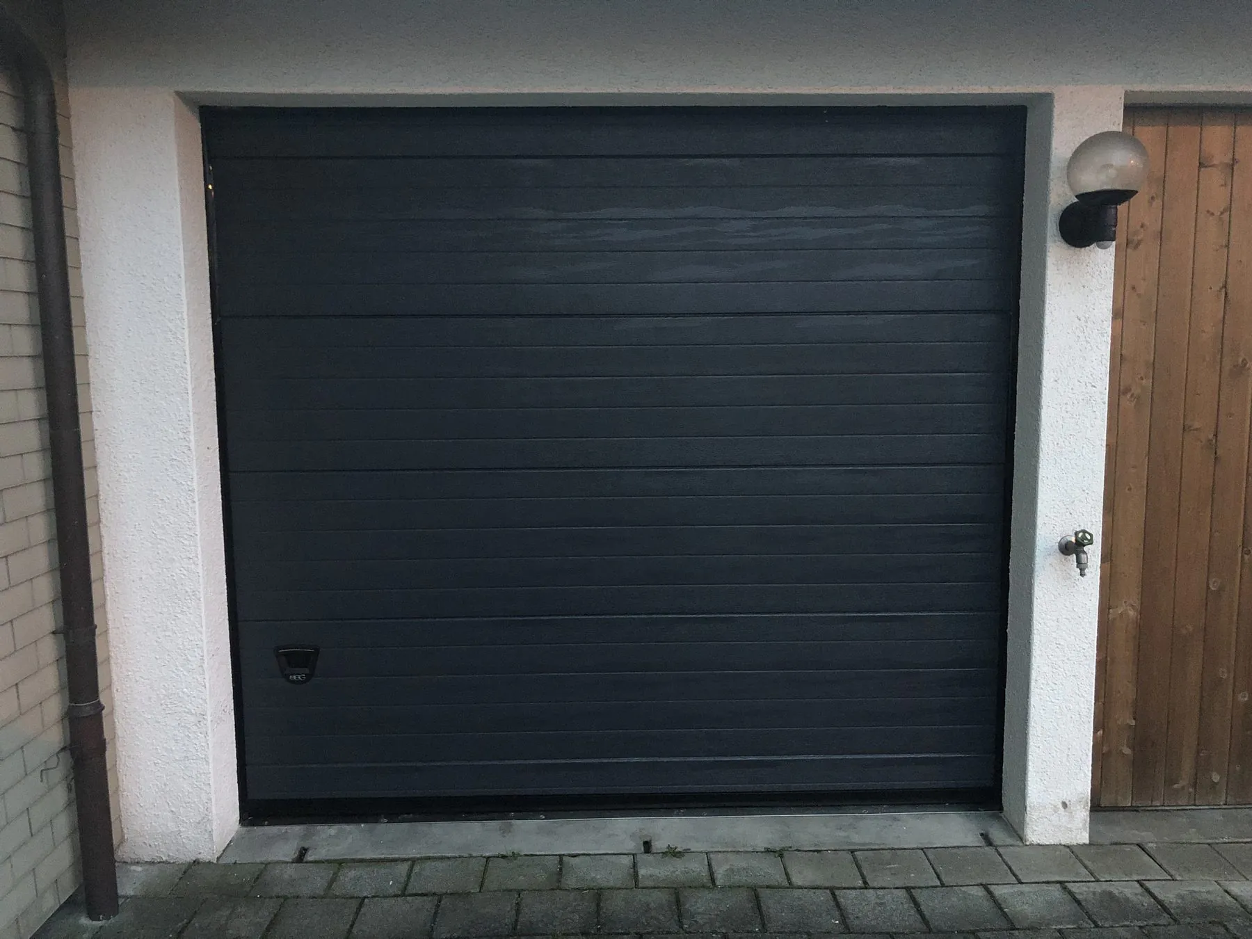 Anthrazitfarbenes Sektionaltor in einer Garage mit Holzverkleidung