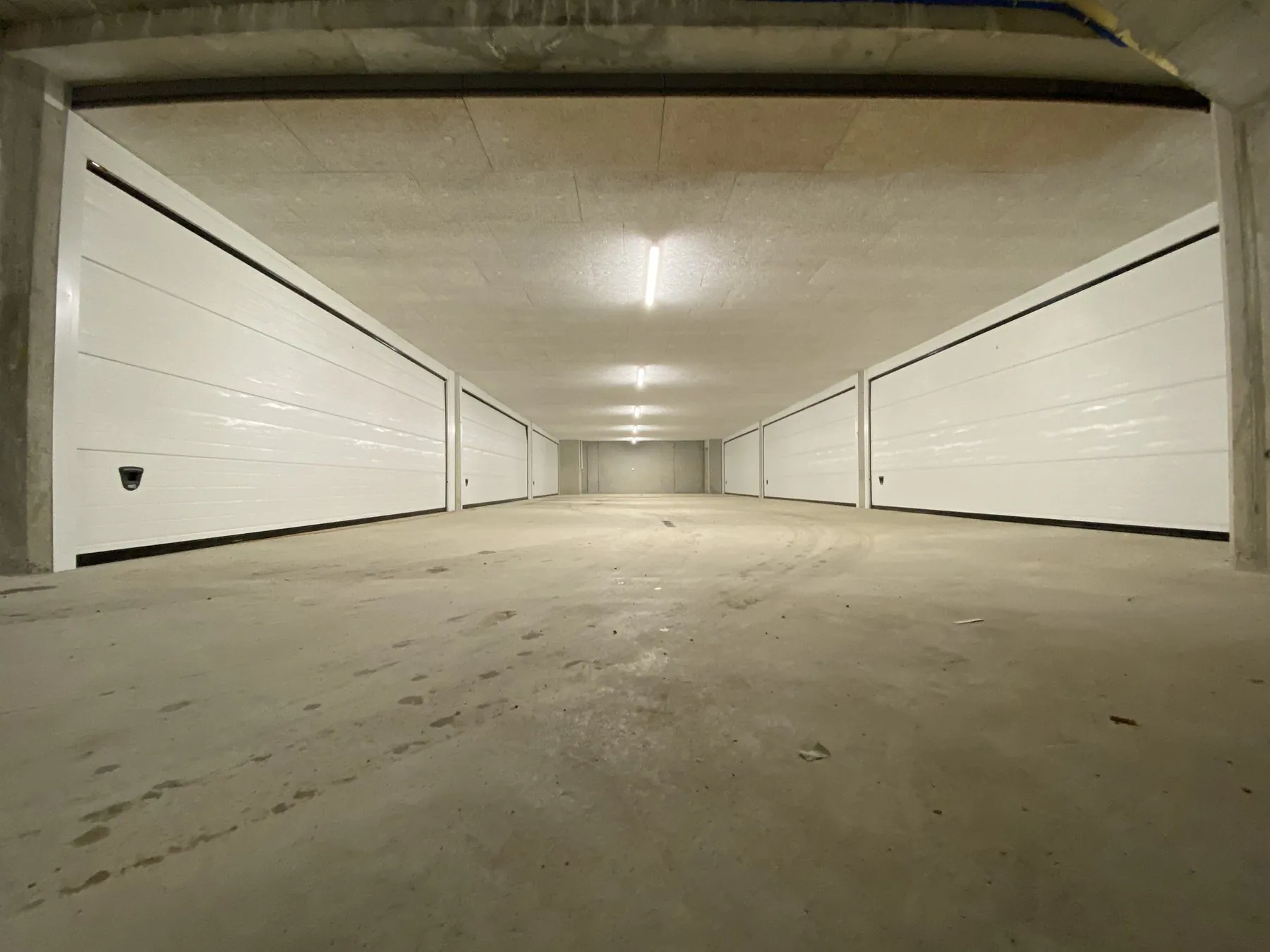 Weisse Sektionaltore an Garagenboxen in einer Tiefgarage