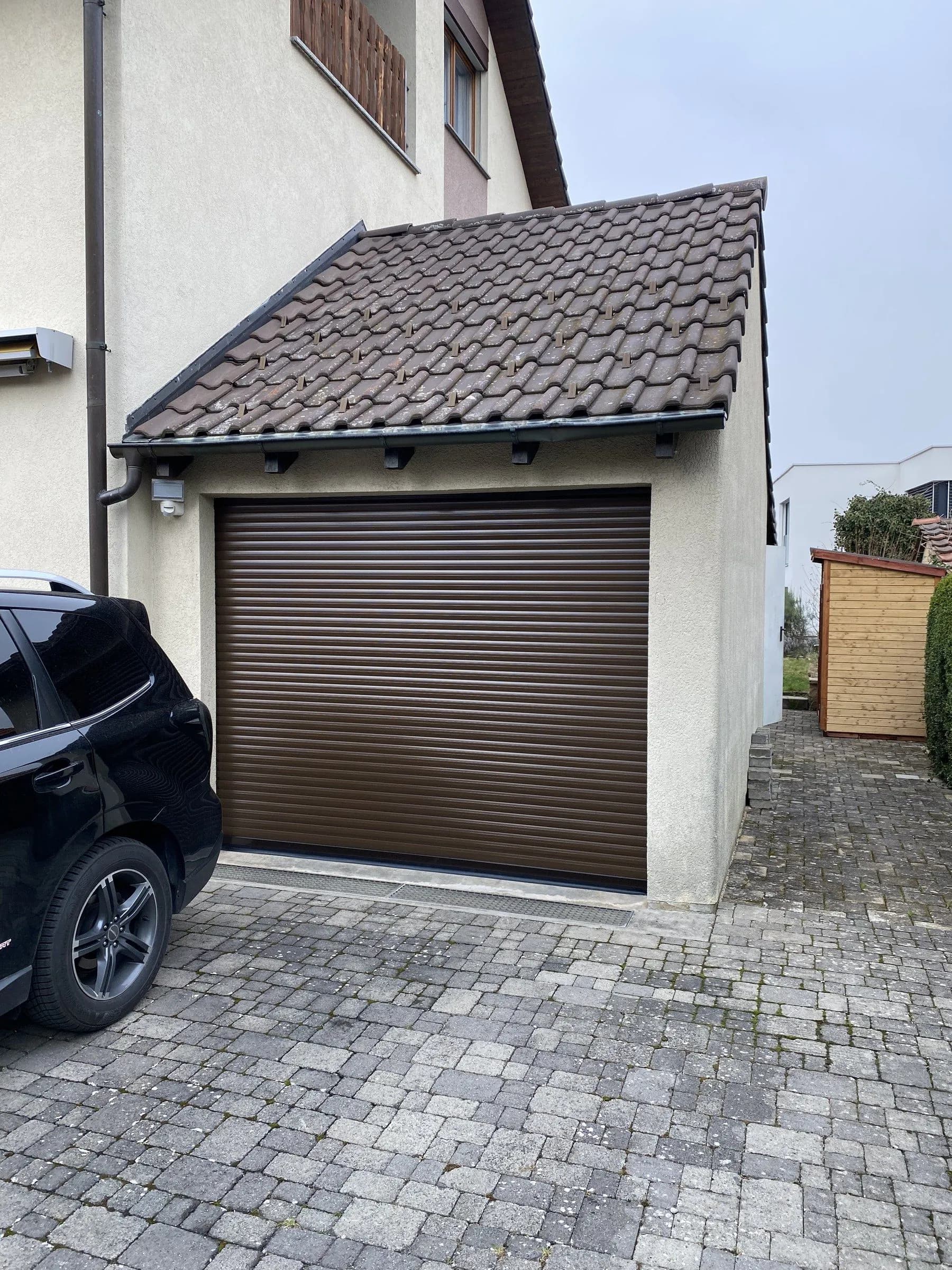 Braunes Rolltor an einer Garage mit gepflasterter Einfahrt