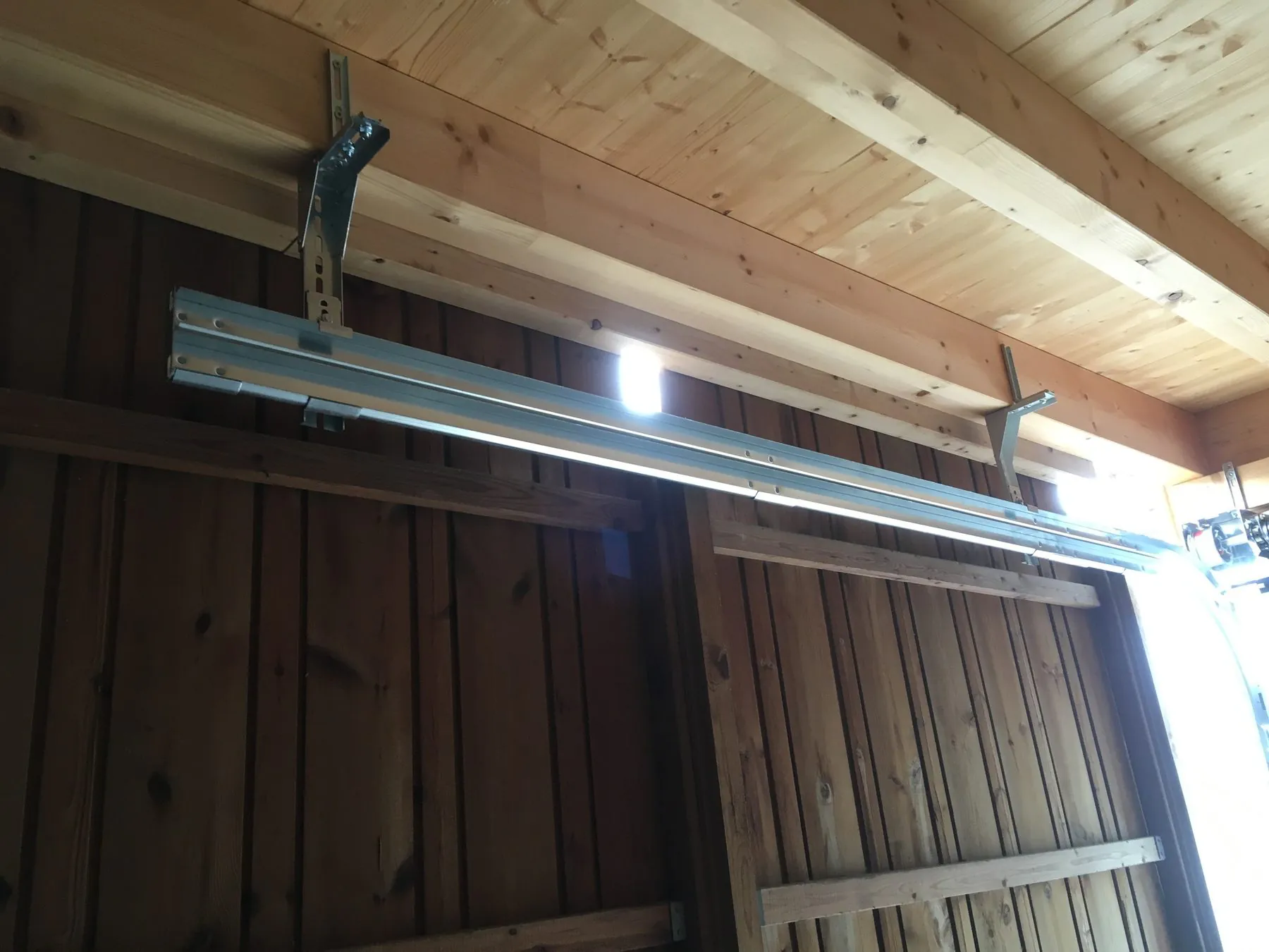 Torantrieb an einer Holzdecke montiert, Schiene und Mitnehmer sichtbar